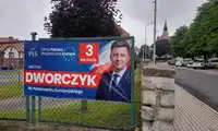 Michał Dworczyk reklamuje się na płocie szkoły